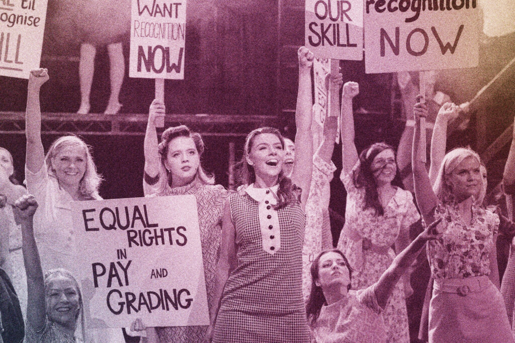 students hold protest signs during a performance of Made in Dagenham