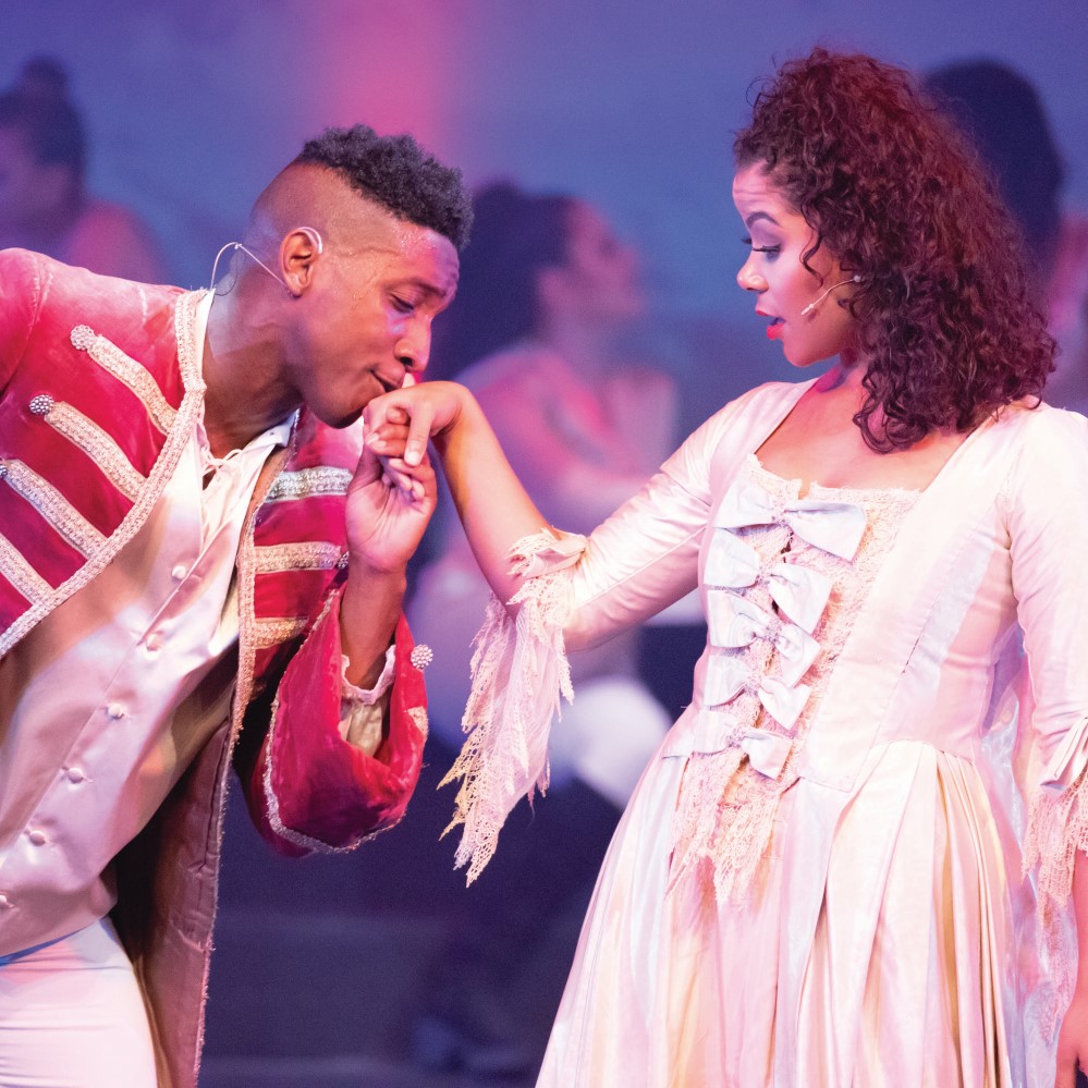 On stage, a Male actor kissing the hand of a female actor