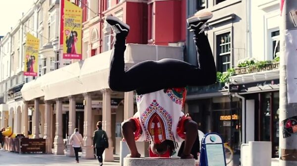 A man executing a handstand at a street corner, demonstrating impressive physical skill amidst the city environment.